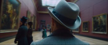 Movie still from “At Eternity's Gate” (2018), directed by Julian Schnabel – A man wearing a white hat in an art gallery; Close Up shot, Over the shoulder angle