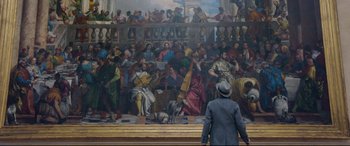 Movie still from “At Eternity's Gate” (2018), directed by Julian Schnabel – A man standing in front of a painting of a crowd; Wide shot, High angle