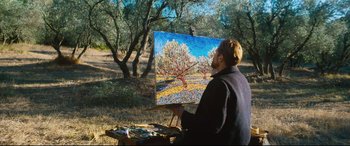 Movie still from “At Eternity's Gate” (2018), directed by Julian Schnabel – A man holding an easel with a painting in front of him; Wide shot, Low angle