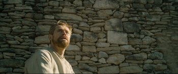 Movie still from “At Eternity's Gate” (2018), directed by Julian Schnabel – A man with a goatee standing in front of a stone wall; Medium shot, Low angle