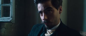 Movie still from “At Eternity's Gate” (2018), directed by Julian Schnabel – A person wearing a suit and tie; Close Up shot, Low angle