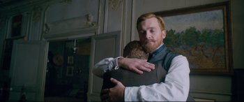 Movie still from “At Eternity's Gate” (2018), directed by Julian Schnabel – A man hugging another man in front of a painting; Medium shot, Over the shoulder angle