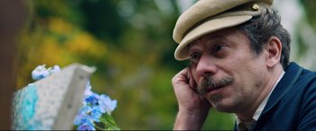 Movie still from “At Eternity's Gate” (2018), directed by Julian Schnabel – A person wearing a hat near a flower; Close Up shot, Low angle