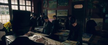 Movie still from “At Eternity's Gate” (2018), directed by Julian Schnabel – A group of people standing in a room with paintings on the wall; Wide shot, High angle