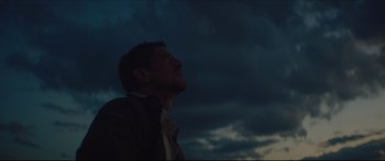 Movie still from “At First Light” (2018), directed by Jason Stone – A man looking up into the sky at night; Medium shot, Low angle