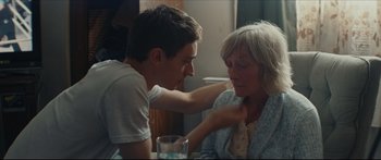 Movie still from “At First Light” (2018), directed by Jason Stone – A young man and an older woman sitting at a table; Medium shot, Over the shoulder angle