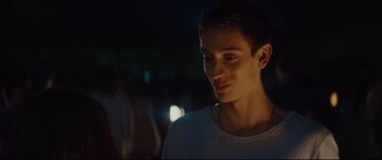 Movie still from “At First Light” (2018), directed by Jason Stone – A young man is smiling for the camera at night; Close Up shot, Over the shoulder angle