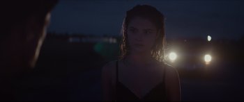 Movie still from “At First Light” (2018), directed by Jason Stone – A woman standing in the middle of a field at night; Close Up shot, Over the shoulder angle