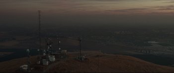 Movie still from “At First Light” (2018), directed by Jason Stone – A view of a city at night from a hill; Extreme Wide shot, Low angle