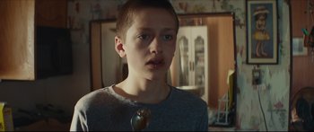 Movie still from “At First Light” (2018), directed by Jason Stone – A young boy is holding a spoon in his mouth; Close Up shot, Over the shoulder angle