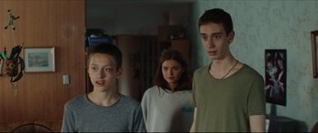 Movie still from “At First Light” (2018), directed by Jason Stone – A group of young people standing in a room together; Medium shot, Low angle