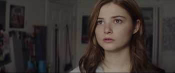 Movie still from “At First Light” (2018), directed by Jason Stone – A young woman with brown hair looking at the camera; Close Up shot, Low angle