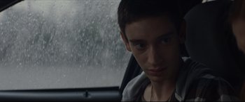 Movie still from “At First Light” (2018), directed by Jason Stone – A man sitting in the driver's seat of a car in the rain; Close Up shot, Over the shoulder angle