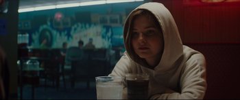 Movie still from “At First Light” (2018), directed by Jason Stone – A person with a hoodie on holding a drink; Close Up shot, Over the shoulder angle