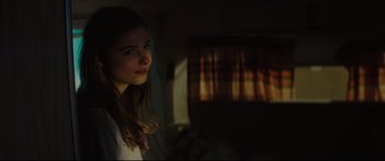 Movie still from “At First Light” (2018), directed by Jason Stone – A girl is standing in a dark room; Close Up shot, Over the shoulder angle