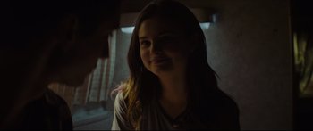 Movie still from “At First Light” (2018), directed by Jason Stone – A woman with long brown hair smiles for the camera; Close Up shot, Over the shoulder angle
