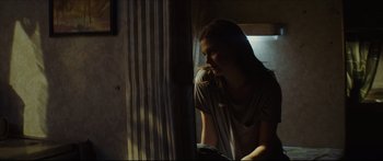 Movie still from “At First Light” (2018), directed by Jason Stone – A woman sitting at a table looking out of a window; Medium shot, Over the shoulder angle