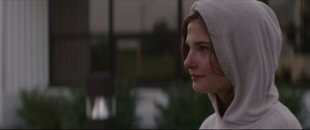 Movie still from “At First Light” (2018), directed by Jason Stone – A young woman wearing a hooded jacket looking to her left; Close Up shot, Over the shoulder angle