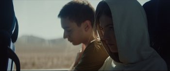 Movie still from “At First Light” (2018), directed by Jason Stone – Two young people sitting side - by - side on a hill; Medium shot, Low angle