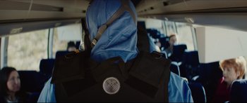Movie still from “At First Light” (2018), directed by Jason Stone – A person wearing a backpack on a plane; Close Up shot, Over the shoulder angle