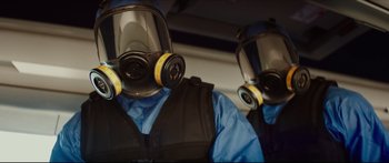 Movie still from “At First Light” (2018), directed by Jason Stone – Two people wearing gas masks in a vehicle; Close Up shot, Low angle