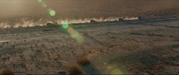 Movie still from “At First Light” (2018), directed by Jason Stone – An aerial view of cars driving down a dirt road; Extreme Wide shot, High angle
