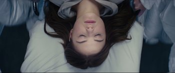 Movie still from “At First Light” (2018), directed by Jason Stone – A woman laying on a bed with her eyes closed; Close Up shot, Overhead angle