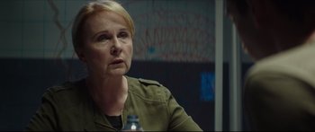 Movie still from “At First Light” (2018), directed by Jason Stone – A woman sitting in front of a glass bottle; Close Up shot, Over the shoulder angle