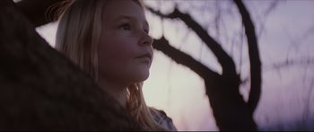 Movie still from “At First Light” (2018), directed by Jason Stone – A young girl looking up into the sky; Close Up shot, Low angle