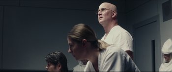 Movie still from “At First Light” (2018), directed by Jason Stone – A man and two women are standing in front of a wall; Close Up shot, Low angle