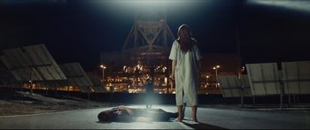 Movie still from “At First Light” (2018), directed by Jason Stone – A woman standing next to a man laying on the ground; Wide shot, Low angle
