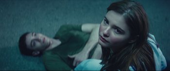 Movie still from “At First Light” (2018), directed by Jason Stone – A woman sitting on the ground looking at the camera; Close Up shot, High angle