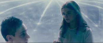 Movie still from “At First Light” (2018), directed by Jason Stone – A woman standing in front of a window; Medium shot, Over the shoulder angle