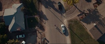 Movie still from “At First Light” (2018), directed by Jason Stone – An aerial view of two cars driving down a street; Extreme Wide shot, Overhead angle