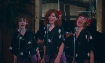 Movie still from “Atlantic City” (1980), directed by Louis Malle – A group of women singing into microphones in front of a mirror; Medium shot, High angle