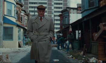 Movie still from “Atlantic City” (1980), directed by Louis Malle – An older man in a trench coat and hat standing on the side of the street; Wide shot, Low angle