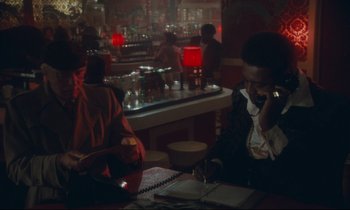 Movie still from “Atlantic City” (1980), directed by Louis Malle – A man sitting at a table talking on the phone; Medium shot, Over the shoulder angle