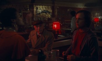 Movie still from “Atlantic City” (1980), directed by Louis Malle – A man and a woman sitting at a table in front of a red lamp; Medium shot, Over the shoulder angle