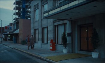 Movie still from “Atlantic City” (1980), directed by Louis Malle – Two people walking down the sidewalk in front of a building; Extreme Wide shot, High angle