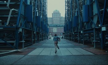 Movie still from “Atlantic City” (1980), directed by Louis Malle – A person running down a street near a tall building; Extreme Wide shot, High angle