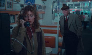Movie still from “Atlantic City” (1980), directed by Louis Malle – A woman talking on a phone while a man in a suit looks on; Medium shot, High angle
