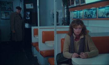 Movie still from “Atlantic City” (1980), directed by Louis Malle – A woman sitting at a table in front of an orange booth; Wide shot, High angle