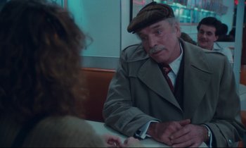 Movie still from “Atlantic City” (1980), directed by Louis Malle – An older man wearing a hat sitting in front of a woman; Medium shot, Over the shoulder angle
