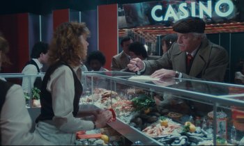 Movie still from “Atlantic City” (1980), directed by Louis Malle – A woman in an apron is standing in front of a counter; Medium shot, Over the shoulder angle