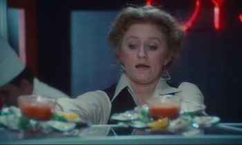 Movie still from “Atlantic City” (1980), directed by Louis Malle – A woman sitting at a table with a plate of food in front of her; Close Up shot, Low angle