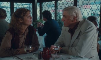 Movie still from “Atlantic City” (1980), directed by Louis Malle – A man and a woman sitting at a table with wine glasses in front of them; Medium shot, Over the shoulder angle