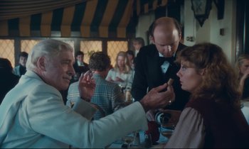 Movie still from “Atlantic City” (1980), directed by Louis Malle – A group of people standing around a table; Medium shot, Over the shoulder angle