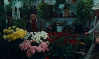Movie still from “Atlantic City” (1980), directed by Louis Malle – A woman standing in front of a table filled with flowers; Medium shot, High angle