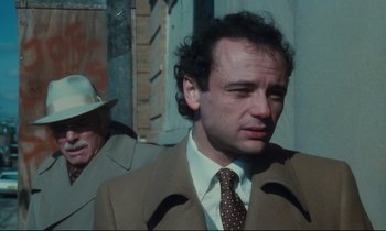 Movie still from “Atlantic City” (1980), directed by Louis Malle – A man in a suit and tie standing next to another man in a hat; Close Up shot, Over the shoulder angle
