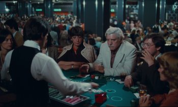 Movie still from “Atlantic City” (1980), directed by Louis Malle – A group of people sitting at a table playing cards; Wide shot, High angle